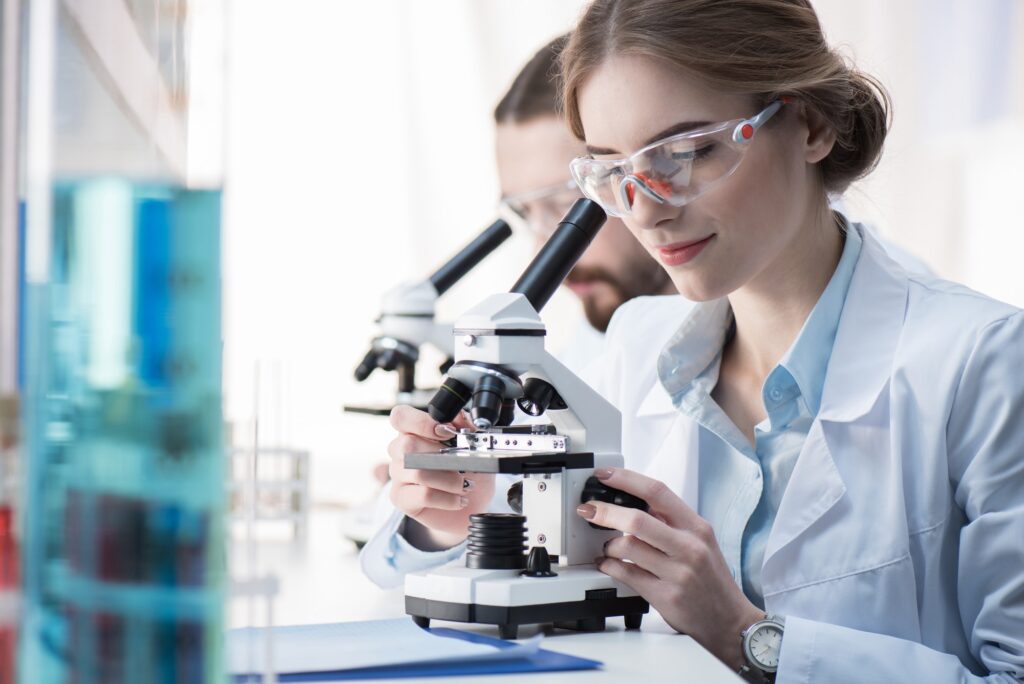 Young female scientist working with microscope in laboratory